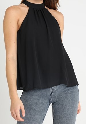 Černý halter top bez rukávů s plisovaným výstřihem, vyrobený z lehké tkaniny, v kombinaci s modrými džínami. Hladká textura, splývavý střih.