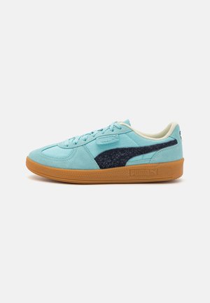 Zapatillas de ante azul claro con un acento azul oscuro, suela de goma texturizada, forro interior beige y cordones clásicos. Logo en el lateral.