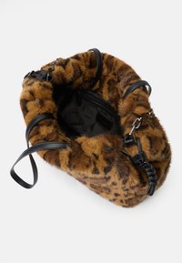 Brūna mākslīgās kažokādas somiņa ar leoparda rakstu, kurai ir melnas ādas akcenti un vairāki nēsāšanas siksnas, tostarp ar pītām detaļām.
