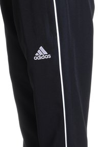 Zwarte sportbroek met witte zijstrepen, vervaardigd uit zacht materiaal, met een geborduurd zilveren Adidas-logo op de linkerdij.