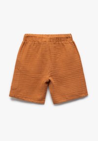 Oranssin väriset puuvillashortsit, joissa on joustavyö ja yksi sivutasku, sekä tekstuurinen, uurrettu pinta.