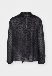 Blusa nera trasparente con dettagli in perline intricati, maniche lunghe e colletto; presenta uno spacco sul retro e un motivo testurizzato su tutta la superficie.