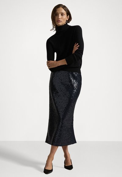 Schwarzer Rollkragenpullover kombiniert mit einem schmal geschnittenen, genadelten, knielangen Rock in dunkelblau. Insgesamt glatte Textur; hoher Kontrastglanz. Schwarze Highheels.