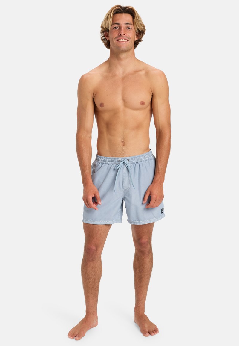 Světlomodré plavky s elastickým pasem a šňůrkou. Obsahují postranní nášivku s logem a mají volný střih. Měkká, strukturovaná tkanina.