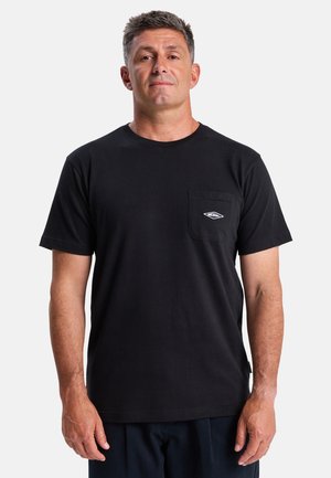 T-shirt en coton noir avec un col rond, des manches courtes et une poche sur la poitrine gauche présentant un logo en forme de diamant. Texture lisse, coupe décontractée.