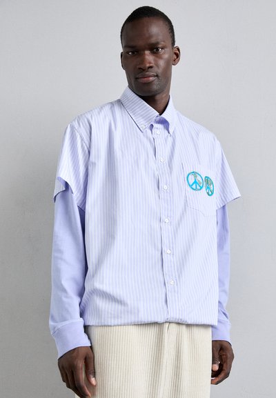 Camicia a maniche corte a righe azzurro chiaro con chiusura a bottoni, dotata di una tasca a toppa decorata con due simboli di pace.