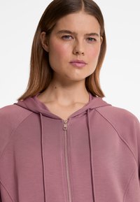 Kapuzensweatshirt mit Reißverschluss in weichem, strukturiertem mauvefarbenem Stoff, mit einem Frontreißverschluss, Kordeln und Raglanärmeln.