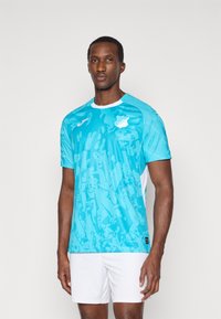 Τυρκουάζ κοντομάνικο μπλουζάκι με υφασμάτινο γραφικό μοτίβο. Διαθέτει λευκό γιακά και πλευρικές λεπτομέρειες, κατασκευασμένο από ελαφρύ, αναπνεύσιμο ύφασμα.