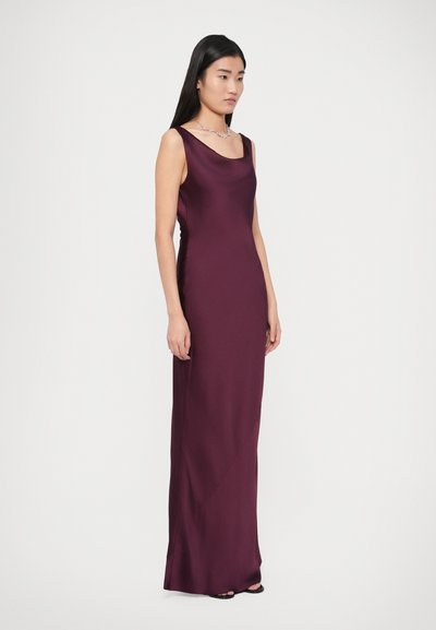 Μακρύ, εφαρμοστό φόρεμα σε βαθύ βουργουνδί σατέν, με τετράγωνο ντεκολτέ, χωρίς μανίκια και διακριτικό σκίσιμο στο πλάι κοντά στο τελείωμα.