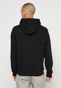Schwarzer Kapuzenpullover mit Kapuze, langen Ärmeln, gerippten Bündchen und Säumen, aus einem glatten Stoff hergestellt. Schlichtes Design, keine sichtbaren Muster oder Akzente.