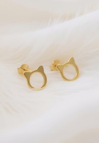 Orecchini a forma di gatto in oro con un ritaglio circolare al centro, con superfici lisce e lucide e un design minimalista.
