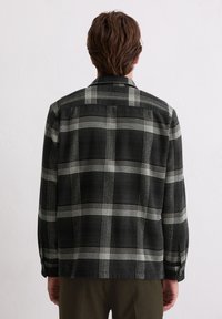 Zwart-wit geruite blouse van stof met een zachte textuur, voorzien van een button-down kraag en lange mouwen met manchetknopen.
