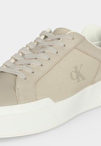 Μπεζ και λευκό αθλητικό παπούτσι Calvin Klein με υφασμάτινα και σουέντ πάνελ, λευκά κορδόνια και χοντρή λευκή σόλα.
