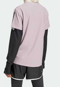 Ljuslila kortärmad skjorta med svarta långärmade tröjor under; har tre svarta ränder på axlarna; kombinerad med svarta shorts.