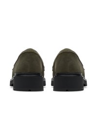 Zapatos de ante verde oliva con un acabado texturizado, que cuentan con una suela de goma negra y un diseño minimalista, vistos desde atrás.