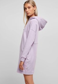 Rochie-hoodie de culoare violet deschis, cu mâneci lungi, glugă și buzunar tip kangaroo. Prezintă un accent mic cu logo aproape de tiv. Textură fină.