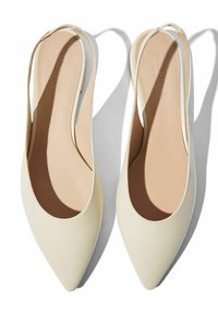Slingback balerinke s uskim otvorom za prste, izrađene od glatke, kremaste kože, s tankim remenom oko gležnja i suptilnim teksturiranim rubom. Ravni đon.