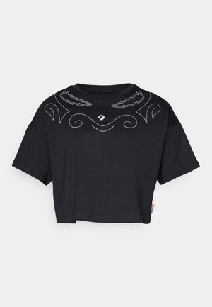 T-shirt noir court à manches courtes, avec une broderie décorative blanche sur la poitrine et une étiquette colorée à l'ourlet.