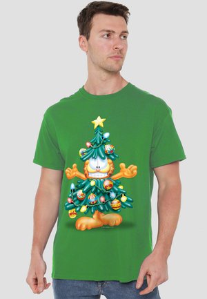 Green cotton t-shirt featuring a cartoon character resembling a cat in a Christmas tree design, adorned with ornaments and lights.
