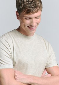 Beige t-shirt met korte mouwen, gemaakt van een zachte, gestructureerde stof, met een ronde halslijn en een klein logo-accent bij de zoom.