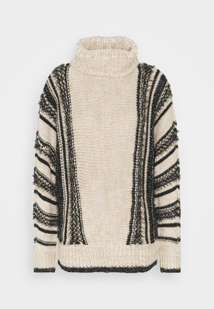Pull en tricot avec un col montant, présentant un corps beige, des rayures noires et des accents frangés sur les manches. Texture douce.