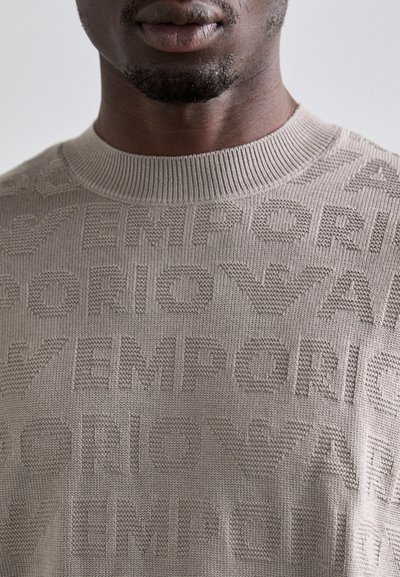Maglione beige a maglia con un motivo testurizzato della parola "EMPORIO" in diverse dimensioni. Collo rotondo e texture liscia.