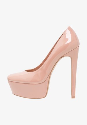 Escarpin en cuir verni nude à semelle plate avec un talon haut aiguille et une pointe arrondie, présenté de profil sur un fond blanc.