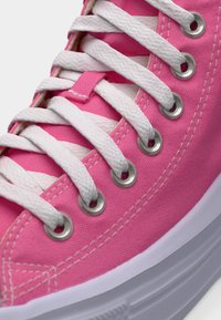 Ροζ καμβά παπούτσι τύπου σνίκερ με λευκά κορδόνια περνώντας μέσα από μεταλλικές τρύπες και παχύ λευκό καουτσούκ σόλα.