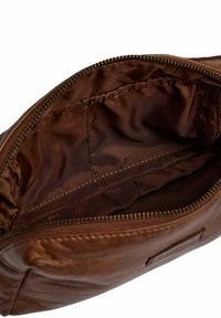 Interno di una borsa in pelle marrone con foderatura in tessuto liscio, dotata di chiusura con zip e dettagli di cucitura ben visibili.