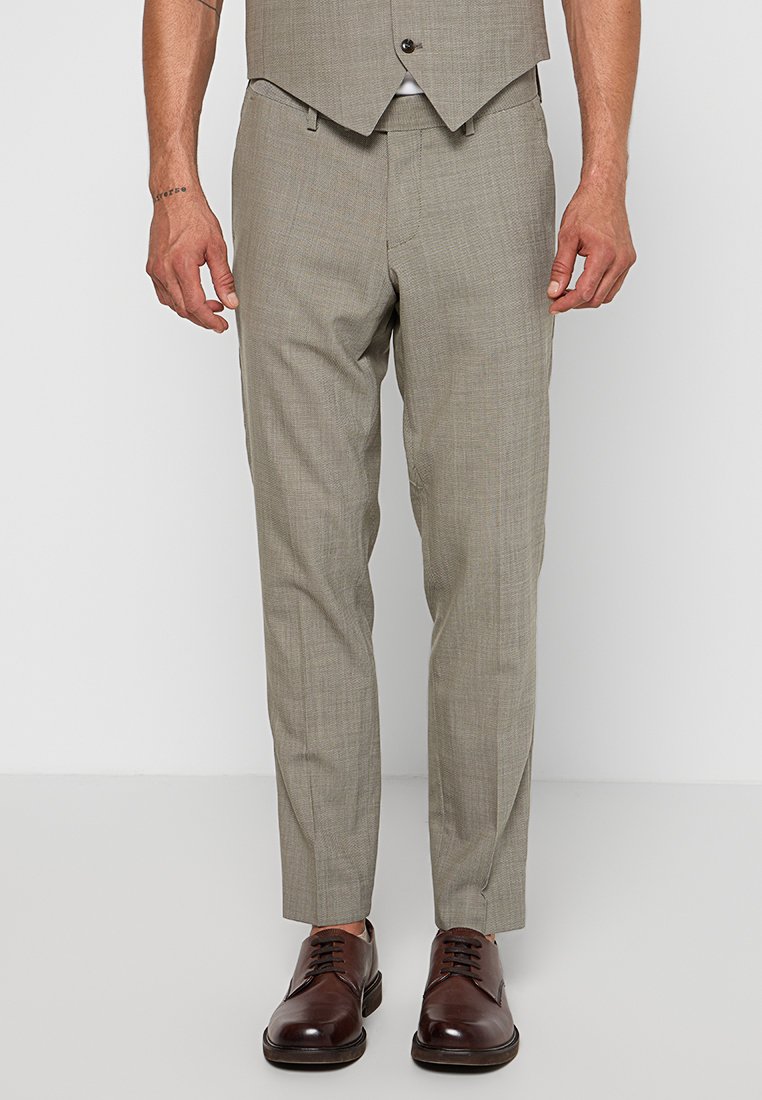 Pantalon de costume gris clair avec un motif texturé et tissé, coupe ajustée et jambes fuselées, associé à des chaussures en cuir marron foncé.