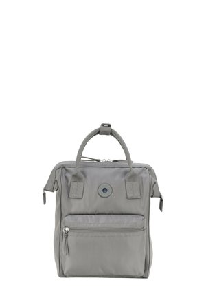 Sac à dos en nylon gris avec une poignée supérieure, une fermeture éclair, une poche zippée avant et un détail de logo circulaire à l'avant.