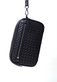 Black woven leather bag with a rectangular shape, zip closure, and a detachable strap. Features a textured surface and metallic hardware accents.