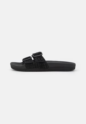 Black slide sandals with two adjustable straps, textured fabric upper, and a cushioned black outsole. Sleek, minimalist design.