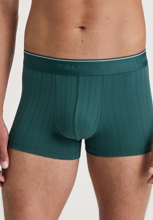 Boxer da uomo verdi a coste con una forma aderente. Presenta una vita a contrasto con il marchio "CALIDA" e un elastico per il massimo comfort.