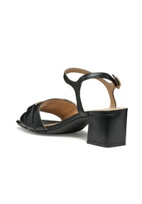 Sandalias de tacón de cuero negro con punta al aire, que cuentan con un diseño de correas entrelazadas y una correa al tobillo con hebilla en tono dorado. Tacón cuadrado.