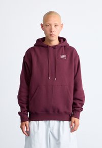 Maroon hoodie made from soft fabric, featuring a front pocket, drawstrings, and a small white Nike logo on the left chest. Simple design.