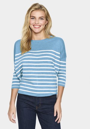 Lysblå stribet sweater med trekvartærmer. Vandrette hvide striber, blød tekstur, afslappet pasform, parret med mørke jeans.