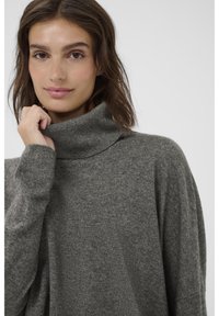 Pelēks augstais kakls džemperis, izgatavots no mīksta adījuma auduma, ar brīvu piegriezumu un garām piedurknēm, ar smalku tekstūru un augstu apkakli.