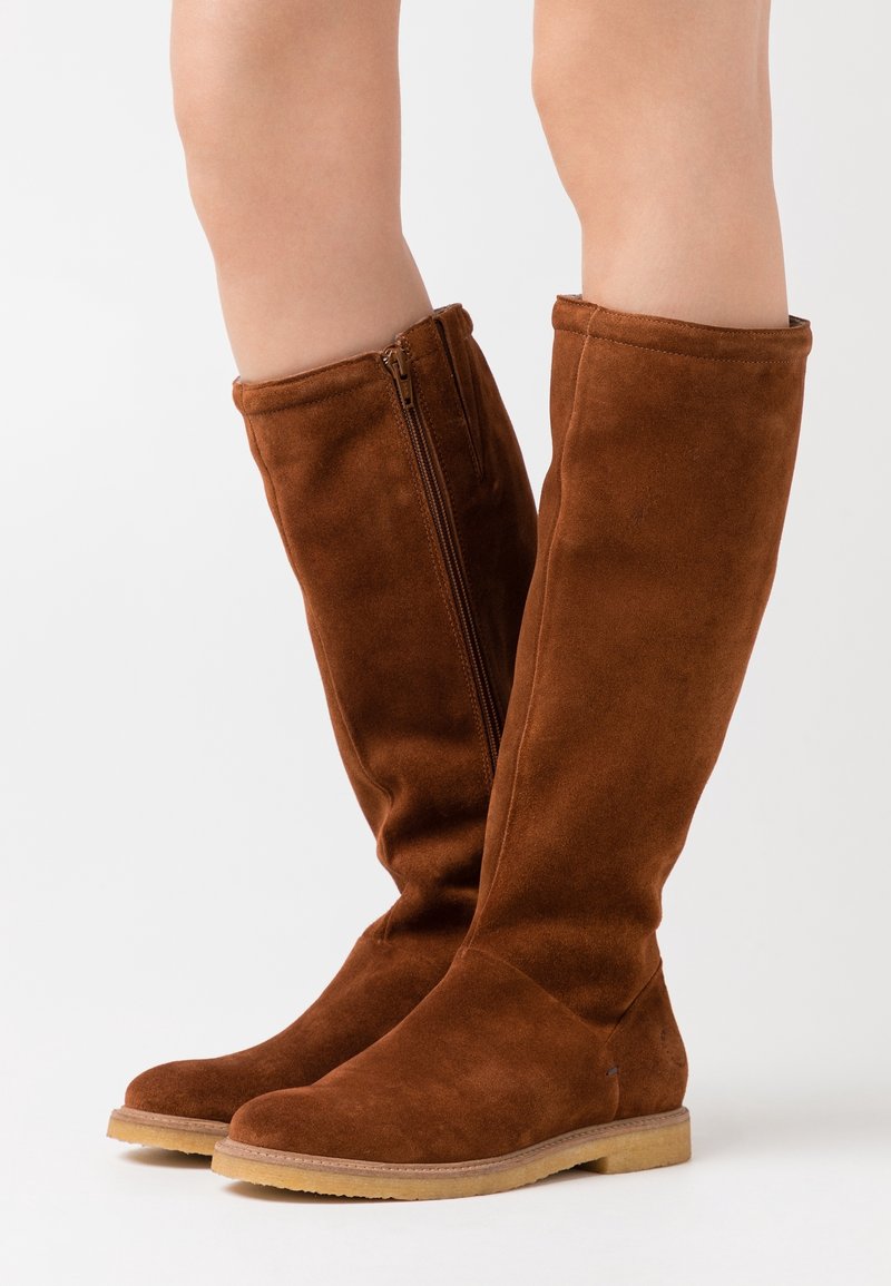 Brown suede knee-high boots with a slim design and side zipper detail, featuring a flat sole and smooth texture.