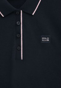 Granatowa koszulka polo z kołnierzykiem, z różowymi akcentami, czterema czarnymi guzikami oraz logo "POLO CLUB" na kwadratowej naszywce z przodu.