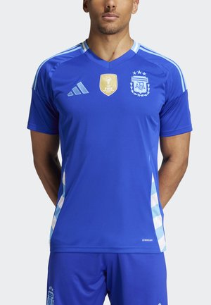 Camiseta de fútbol azul con cuello en V, con rayas azul claro en los hombros. Emblema dorado de la FIFA y logo de Argentina prominentes en el pecho.