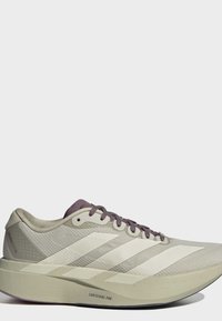 Chaussure de course légère beige avec trois bandes blanches, des lacets violets et une semelle épaisse nommée Lightstrike Pro.
