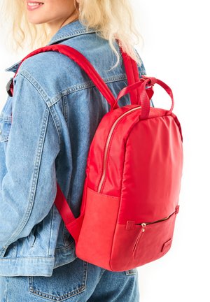 Red nylon backpack with a smooth texture, padded straps, and a zippered front pocket. The design is rectangular with rounded edges.