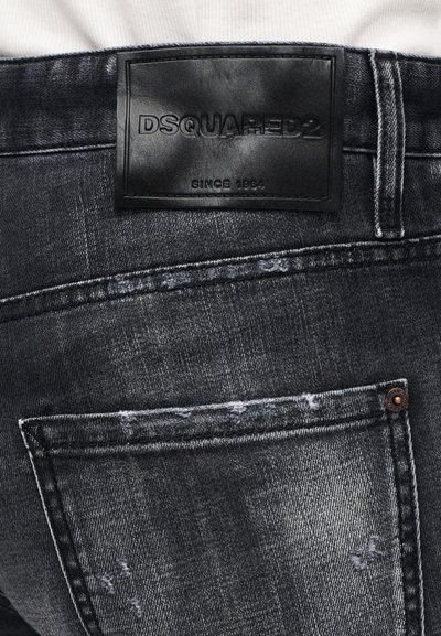 Σκούρα τζιν από ντένιμ με υφή, με μαύρη δερμάτινη ετικέτα στη μέση και φθαρμένες λεπτομέρειες στις πίσω τσέπες.