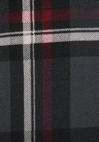 Black, gray, and red plaid fabric features a repeating pattern of broad and narrow stripes with fine textures and contrasting lines in white.