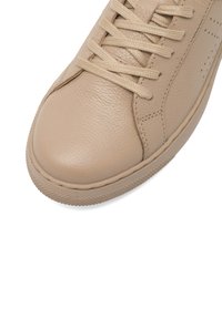 Beżowe skórzane sneakersy z okrągłym noskiem, teksturowanym wierzchem, dopasowanymi sznurowadłami i gumową podeszwą. Zawierają małe perforacje dla wentylacji.