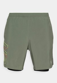 Zelené sportovní šortky s elastickým pasem, s výrazným grafikou ve žluté a červené barvě na levé straně a vnitřní černou vrstvou.