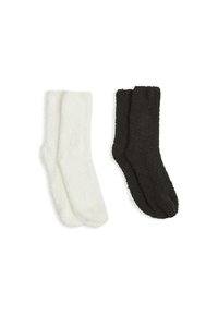 Due paia di calzini pelosi: uno bianco e uno nero. Entrambi hanno una consistenza morbida e un design standard di lunghezza crew.