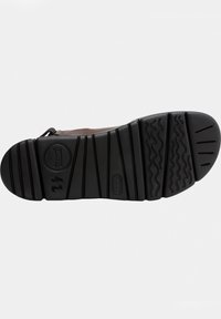 Black rubber sole with textured tread patterns; features a circular logo and size markings on the surface, designed for grip and durability.