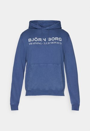 Zils kapuce, kas izgatavota no mīkstas auduma, ar kangurū kabatu, ar priekšējo tekstu: "BJÖRN BORG TRENINGA KLUBS MONAKĀ," un regulējamu auklu kapuci.